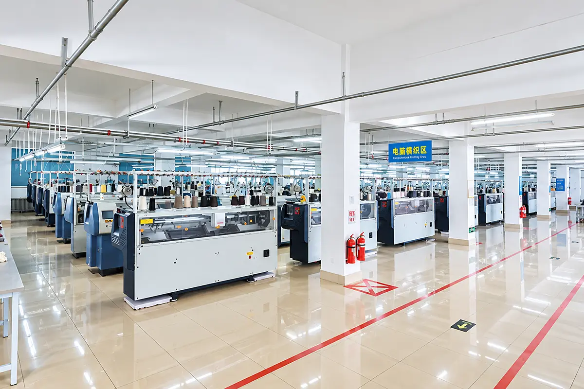 Rows of computerized flat knitting machines in the production workshop.