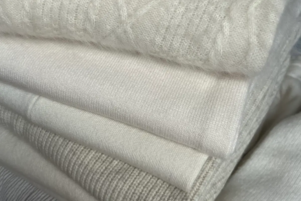 Stacked cream knit fabrics showing different surface textures.