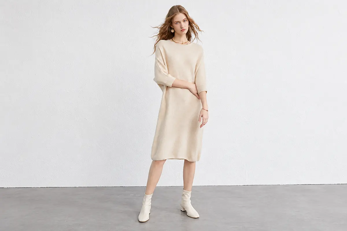 Cream knee-length knit dress with three-quarter sleeves.