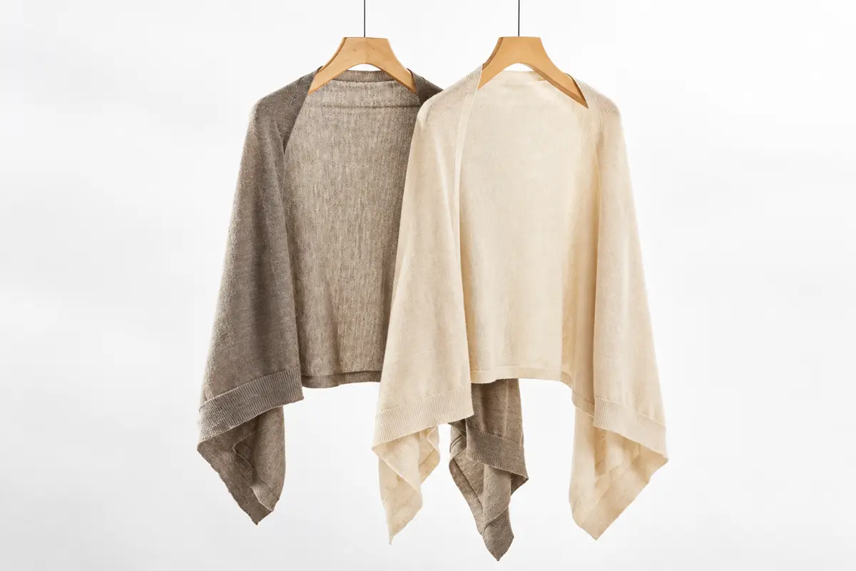 Taupe and cream knit wraps on wooden hangers.