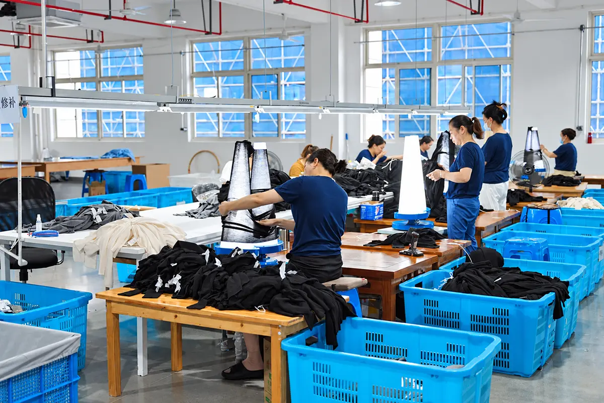 Factory workers handling garments at worktables.
